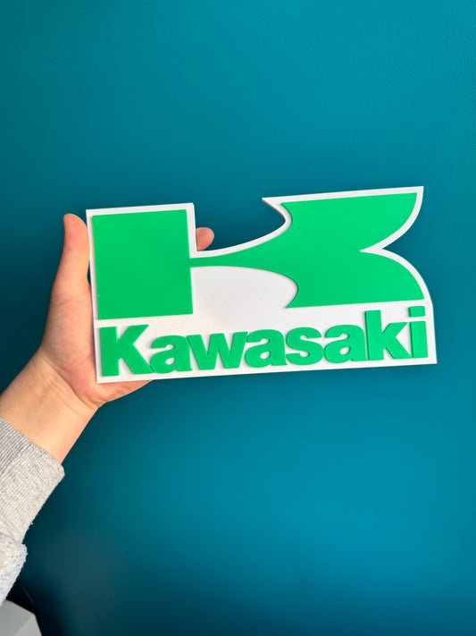 Logo Kawasaki en relief 3D, finition lisse et design fidèle.

